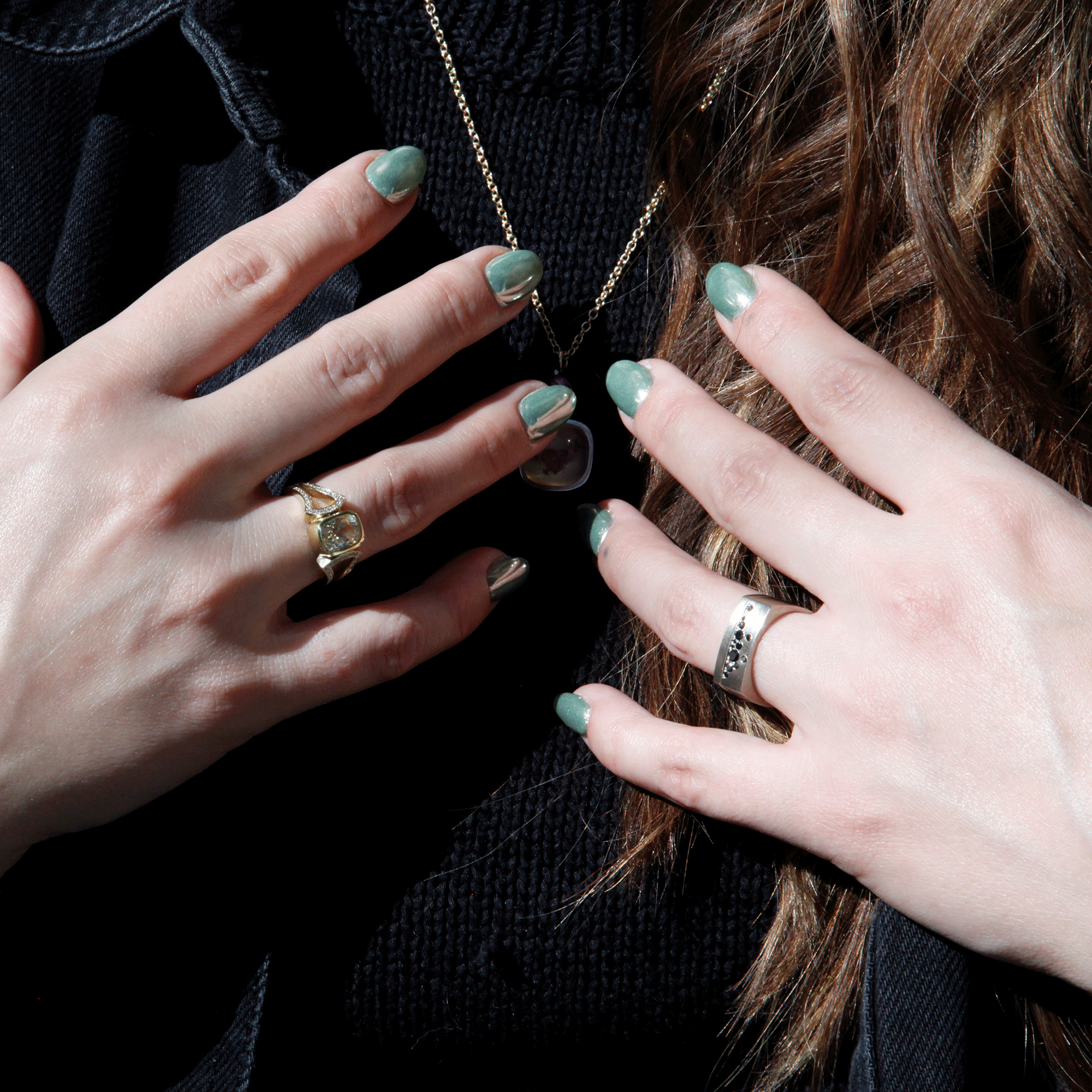 Lady touching her necklace and showcasing her rings.