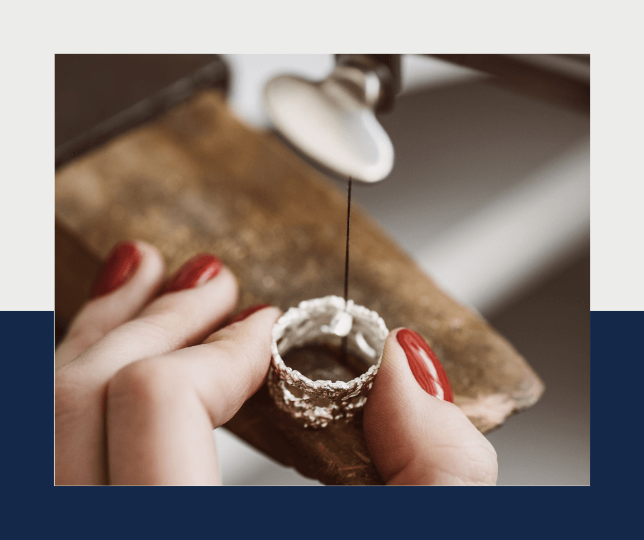 woman hands holding a ring on her bench pin and sizing a ring.