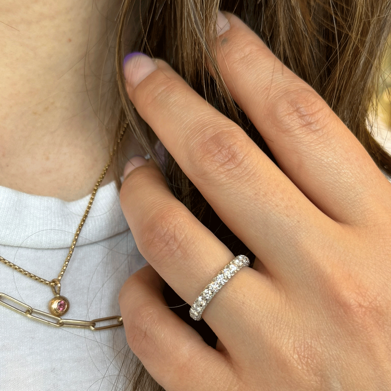 A delicate necklace is also visible around her neck. The background is blurred, focusing attention on the jewelry.