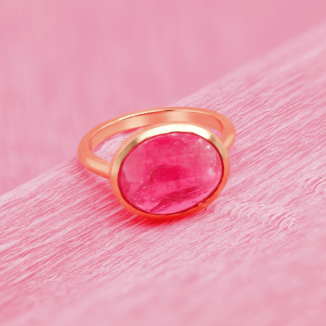 18k yellow gold ruby cabochon solitaire ring, front view. Sitting on pink paper