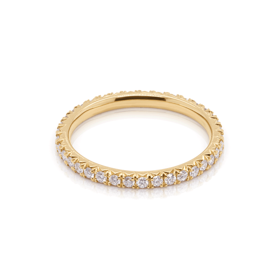 Delicate lab-grown diamond eternity ring in 18K yellow gold, crafted in a celestial comet tail style. Top view on white background.