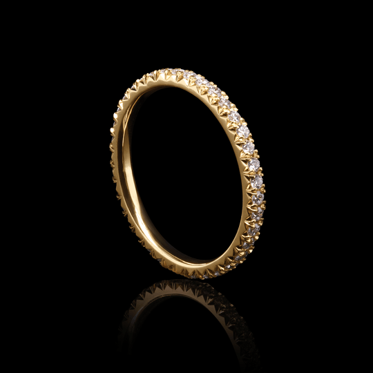 luminous 18K yellow gold eternity ring with lab-grown diamonds, capturing the essence of a celestial comet tail. 3 Quarter view of ring on black background.