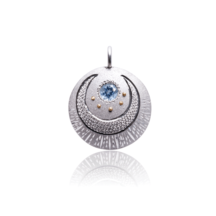 Luna charm pendant in sterling silver with blue topaz and gold details, celestial-inspired design by Janine Jewels.