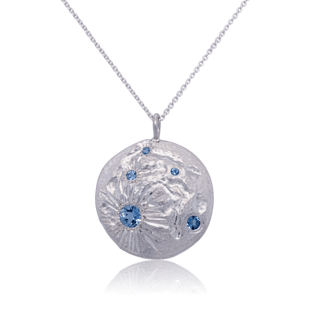 Handcrafted sterling silver Luna pendant with blue topaz gemstones, inspired by celestial textures and artisan craftsmanship.