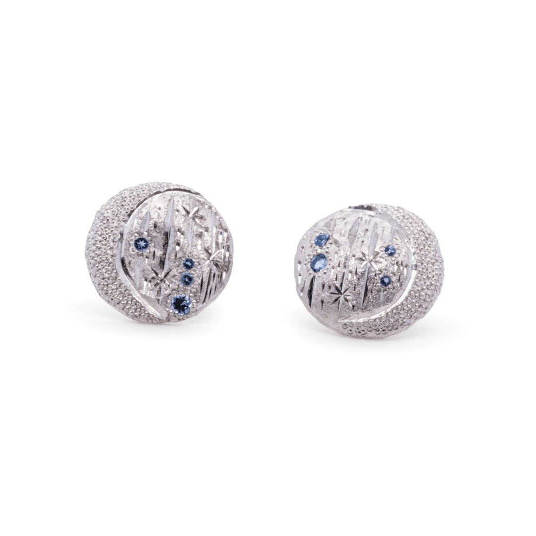 Sterling silver celestial-inspired earrings with hand-engraved textures, blue topaz accents, and crescent moon design by Janine Jewels.