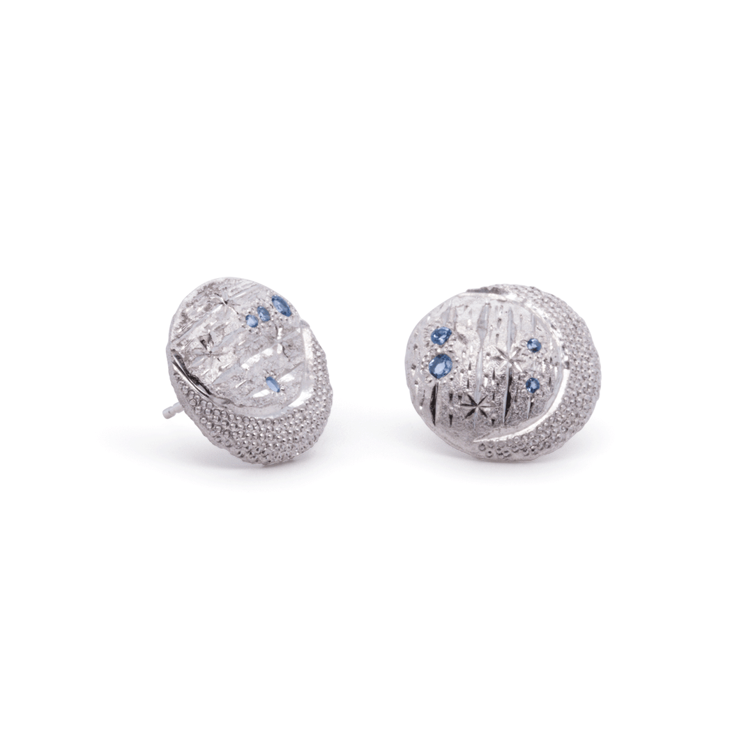 Celestial silver earrings with textured surfaces, blue topaz accents, and crescent moon and starburst design, handmade by Janine Jewels.