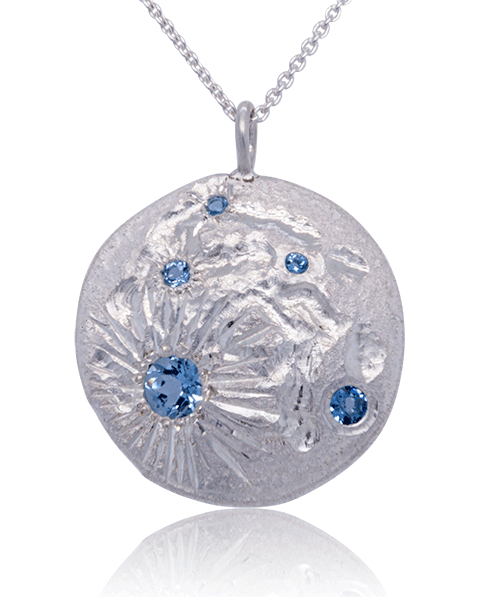 Janine Jewels’ custom-designed Luna pendant featuring textured silver and sparkling blue topaz – a unique artistic statement piece