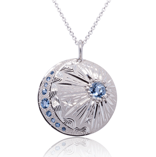 Sterling silver starburst pendant necklace with crescent moon detail and blue topaz accents, artisan-crafted by Janine Jewels.