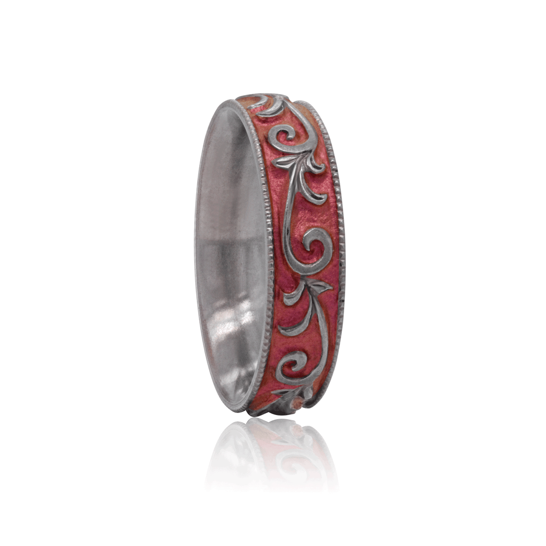 Angled view of pink anodized titanium ring with hand-engraved vine pattern, 5mm wide, displayed against a white background.