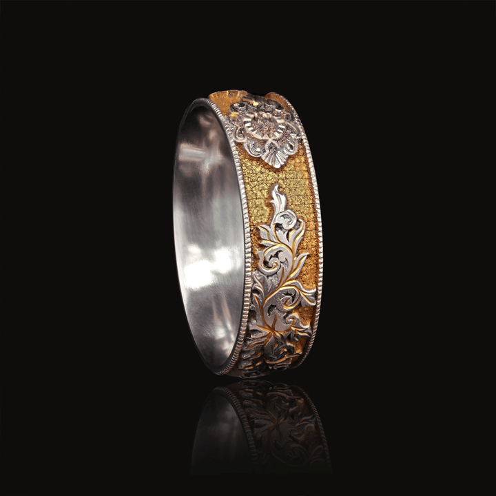 Angled view of titanium ring with rich gold finish, featuring hand-engraved lock and scroll design, displayed on a black background.