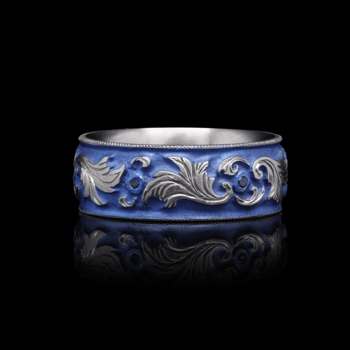 Front view of Lagoon Lustre titanium ring in blue, showcasing detailed scroll engraving with sapphire accents, on a black background.