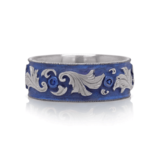 Blue anodized titanium ring with lab-grown blue sapphires and vintage-inspired scroll engraving, displayed against a white background.